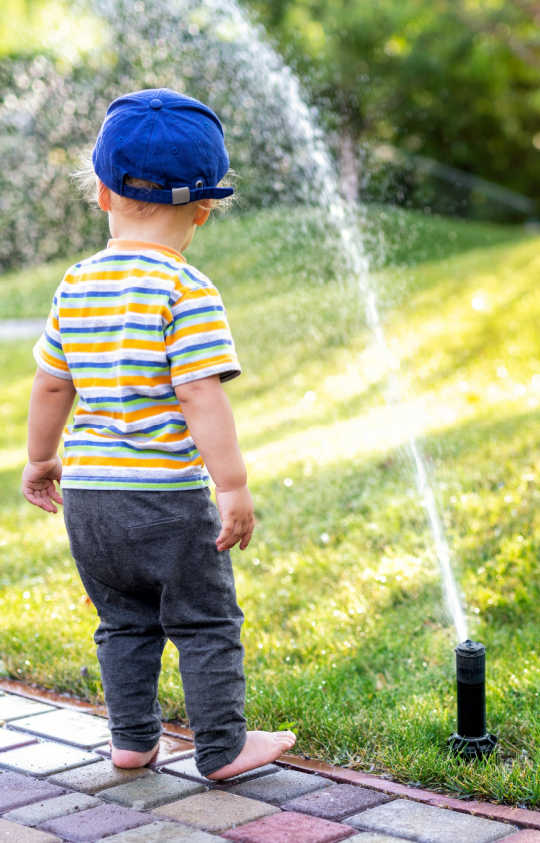 Boy in sprinkler - yard maintenance